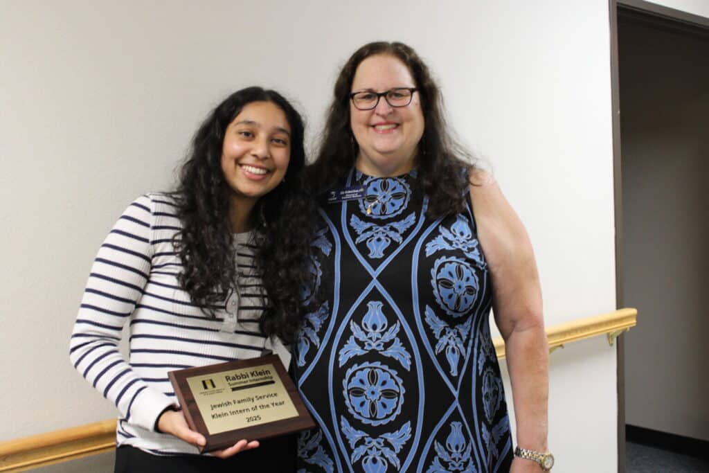 Two women smiling; one holds a plaque that reads "Jewish Family Service, Klein Intern of the Year, 2024.