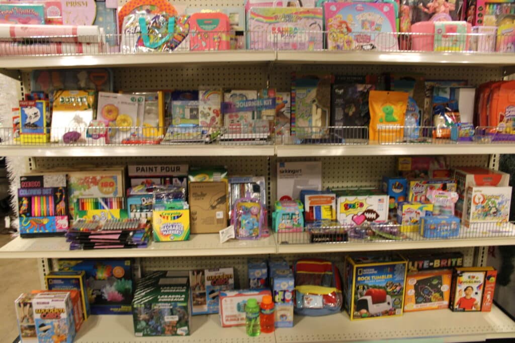 Shelves filled with colorful children's toys, art supplies, coloring books, games, and activity kits in a store.