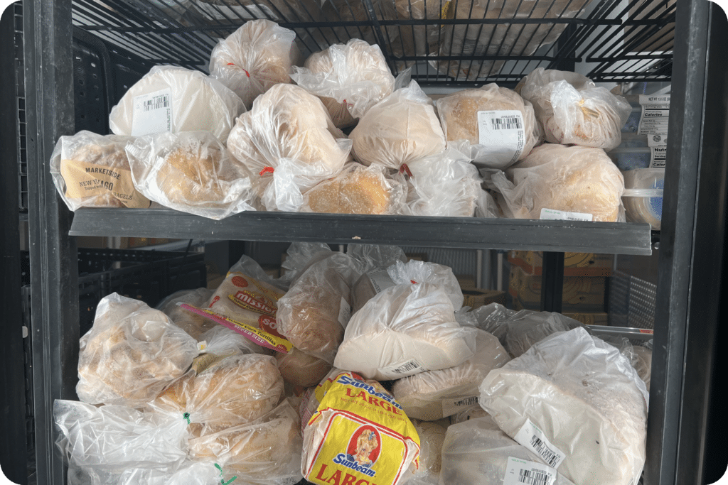 Shelves in the JFS Dallas Food Pantry freezer stocked with rescued bread, bagels, buns, and other bakery items donated by local retail partners.