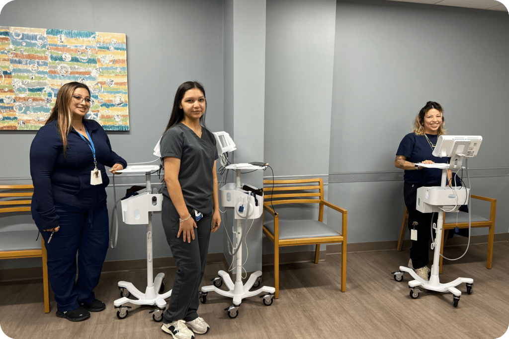 Three JFS Dallas medical staff members stand beside mobile health screening stations, ready to provide blood pressure screenings during the Back-to-School Health Fair.