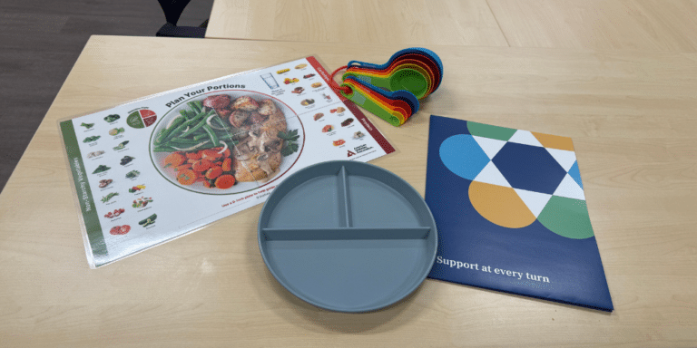 Nutrition education materials, measuring cups and a portioned plate used during nutrition services at JFS Dallas.