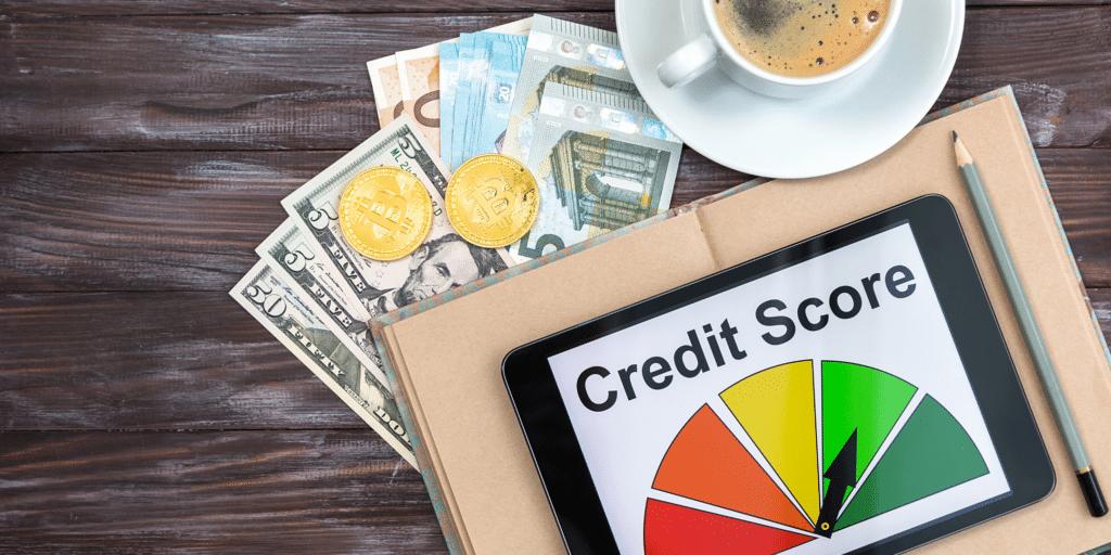 A tablet displaying a green credit score gauge, placed on a notebook with cash, two coins, and a cup of coffee.